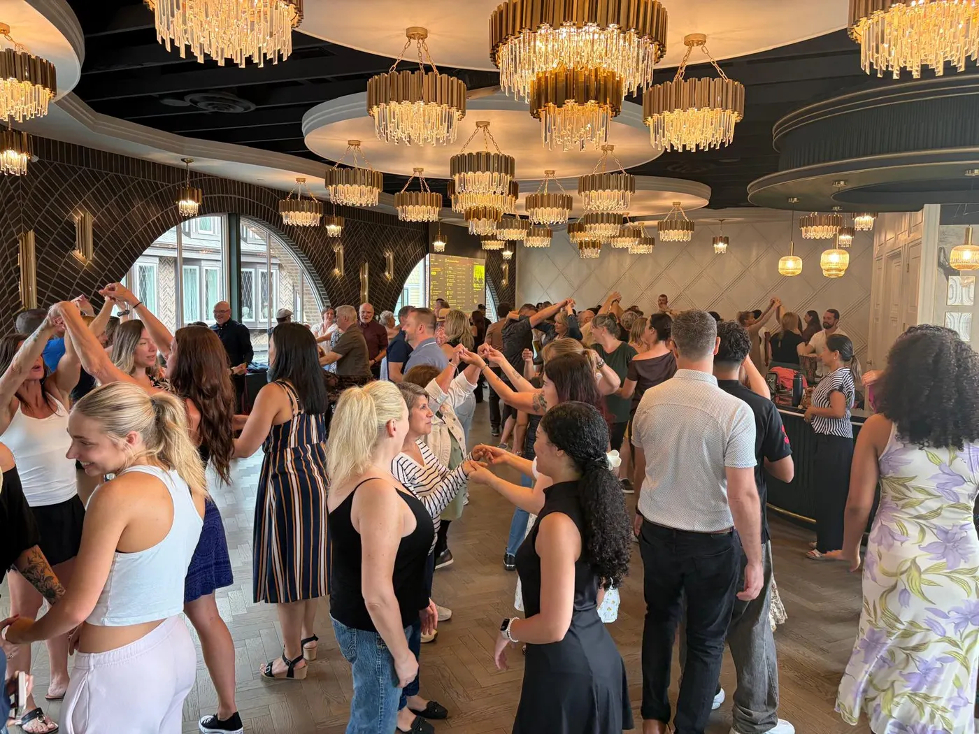 A packed dance floor at The Grand Hall, District 1881 in Chilliwack — around eighty people paired up under the art deco chandeliers on launch night of Tuesday Salsa Nights