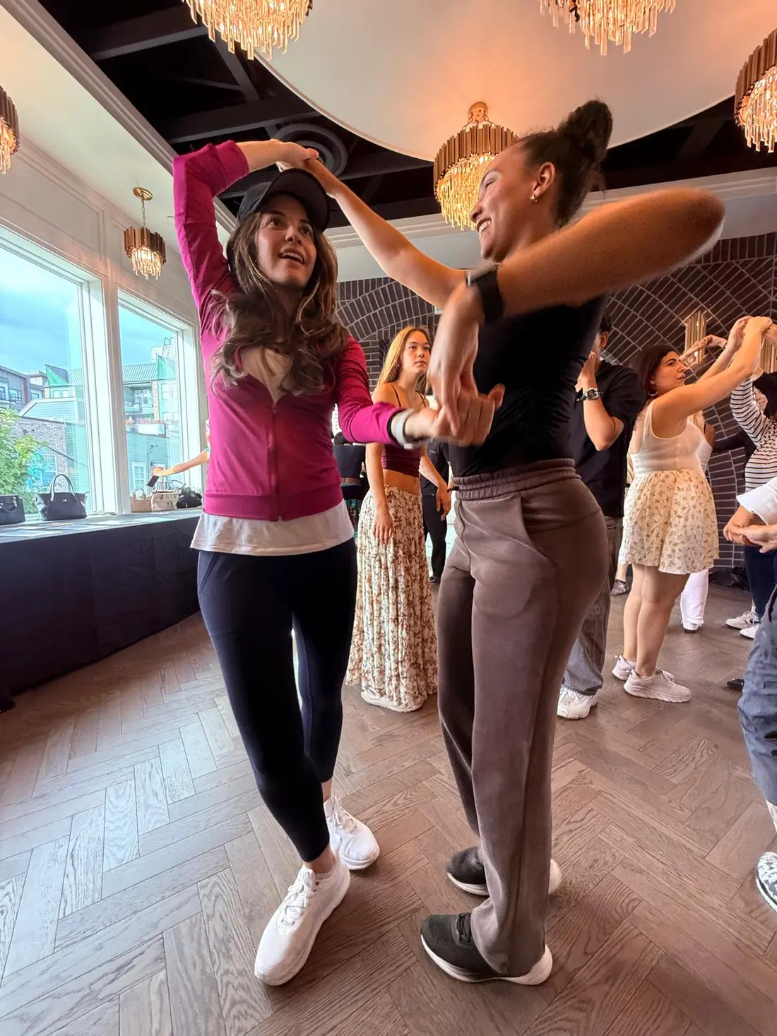 Two dancers connecting through a turn under the chandeliers