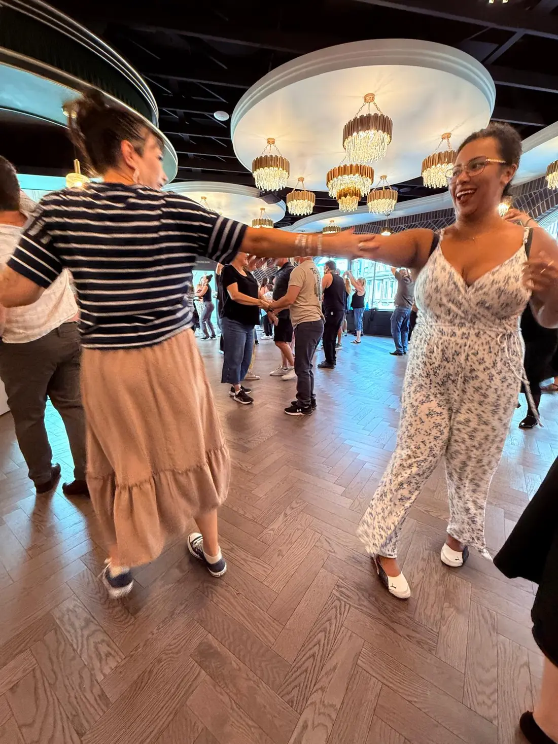 Dancers with joined hands raised, mid-pattern, during the merengue lesson