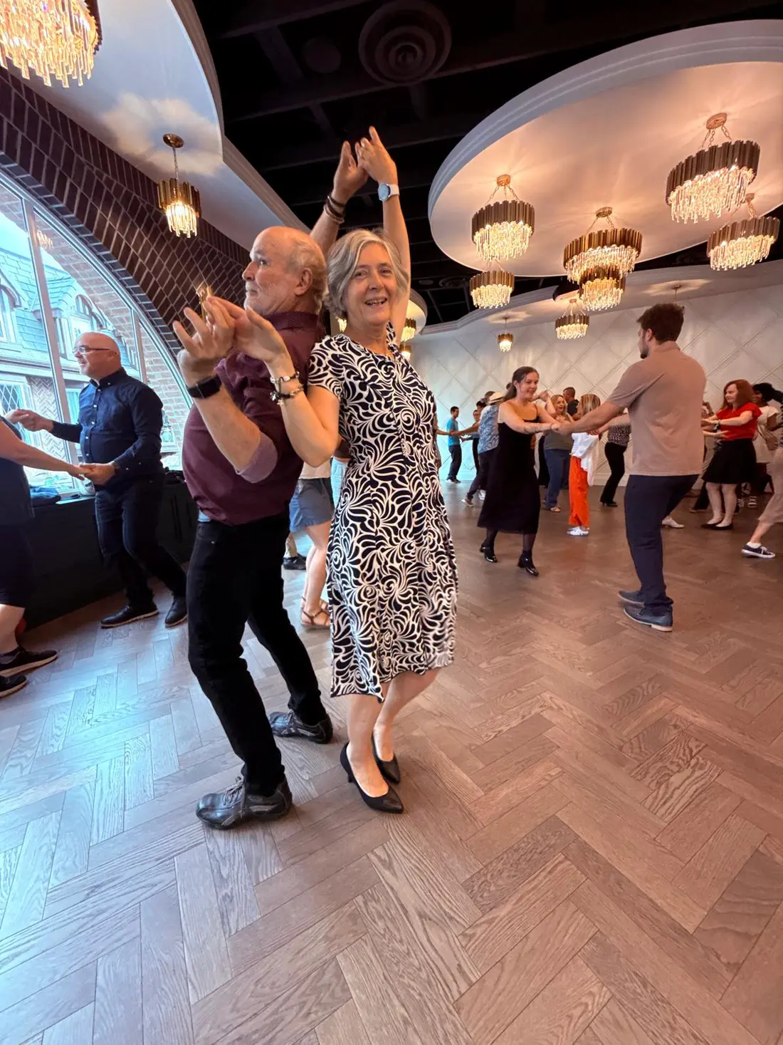 Two dancers turning past each other with arms extended
