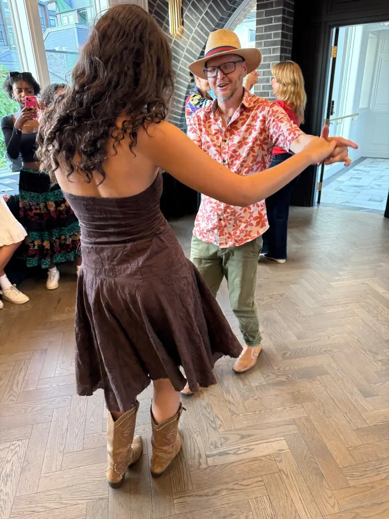 Salsa Paul in a straw hat leading a follow through a turn during open social dancing at The Grand Hall, Chilliwack