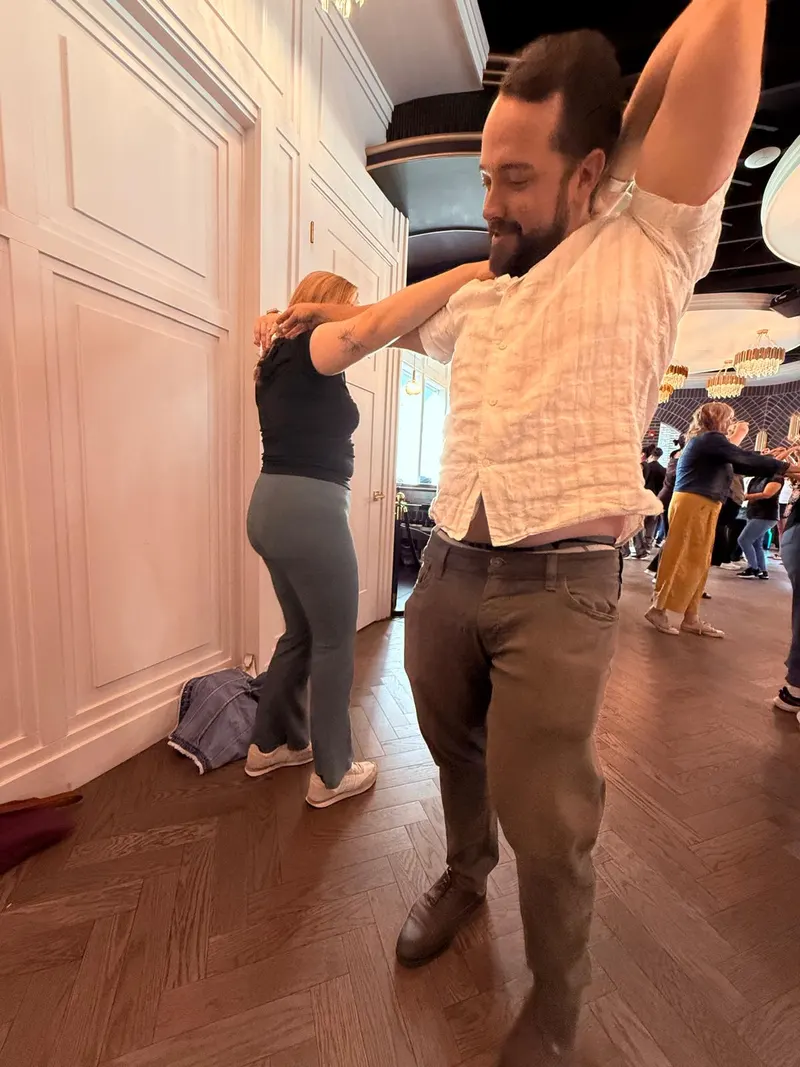 A dancer bringing a joined hand behind their own head during the sombrero