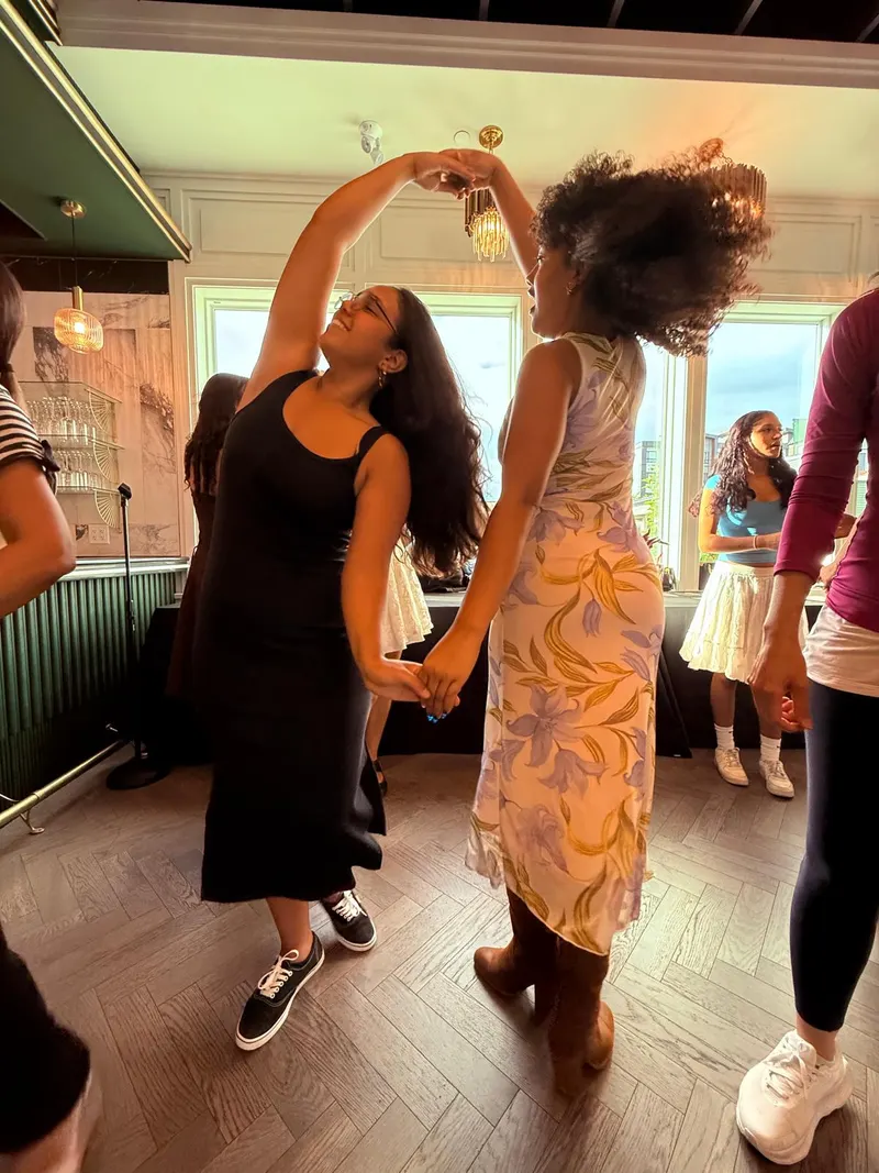 A follow turning under the lead's raised arm during the windmill in a beginner merengue lesson in Chilliwack